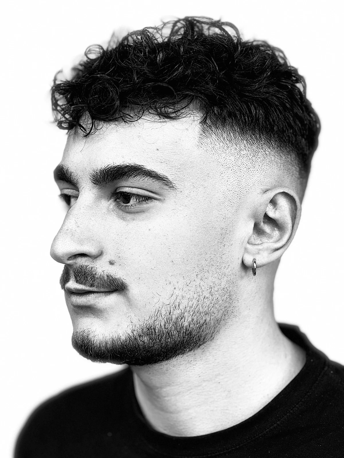 Lucrare Ștefan Jicarean — top cu bucle și skin fade, conturare barbă, profil alb-negru